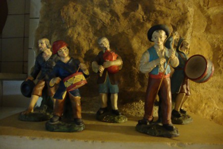 Cinco imagens de presépio, com medidas entre 23 e os 26 cm de altura. Três musicos e dois pastores. Uma imagem apresente colagens e o tocador de gaita de foles apresenta uma falha.