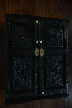 Pequeno armário/contador em madeira trabalhada e pintada de preto. Apresenta ainda 4 botões originais de madrepérola. O interior tem uma gaveta pequena na base..
