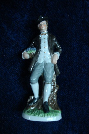 Figura masculina com cesta de uvas em porcelana policromada. Anos 40.