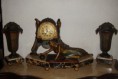 Relógio de pêndulo, art deco, assinado e marcado "France".  Apresenta duas anforas laterais e a composição central é feita por uma figura feminina tipicamente vestida à época a brincar com bola.  A peça tem a base em marmores multicolores e as esculturas 